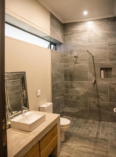 a bathroom with a shower and a sink and a toilet at Oudewerfskloof Olive Farm in Stilbaai