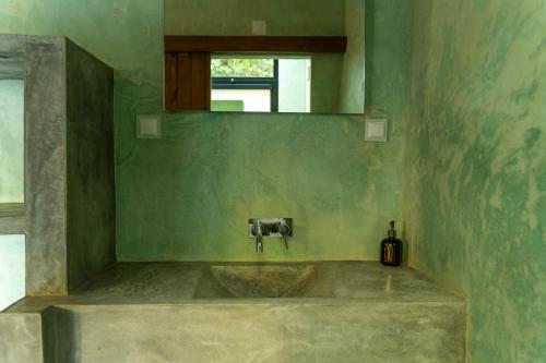 a green bathroom with a sink and a mirror at Casa de São Roque in Avis