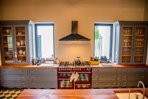 a kitchen with a stove and some windows at Oudewerfskloof Olive Farm in Stilbaai