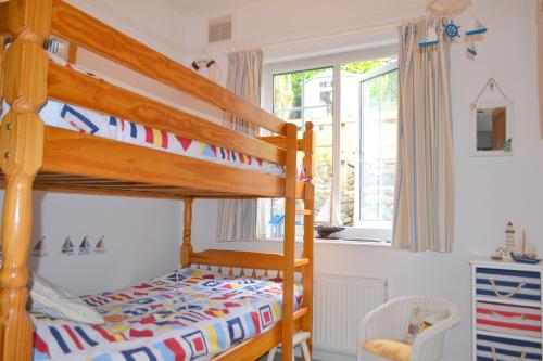a childs bedroom with bunk beds and a window at Lighthouse Cottage, 19 Broadlands, Shaldon in Shaldon