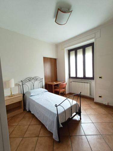 a bedroom with a bed and a desk and a window at OSTELLO del Lago in Grottaferrata