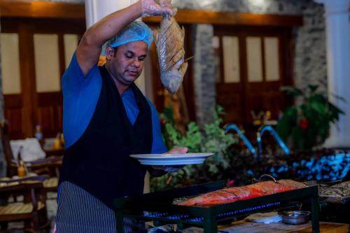 a woman is holding a plate of food at Kandahena Mansion in Akuressa