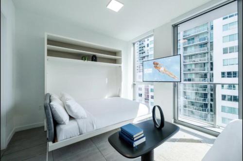a white bedroom with a white bed and a window at Spacious Studio in the Heart of Downtown Miami in Miami
