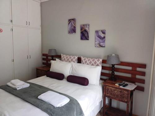 a bedroom with a large white bed with two tables at Orchard Guesthouse in Bloemfontein