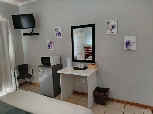 a room with a mirror and a sink and a microwave at Orchard Guesthouse in Bloemfontein