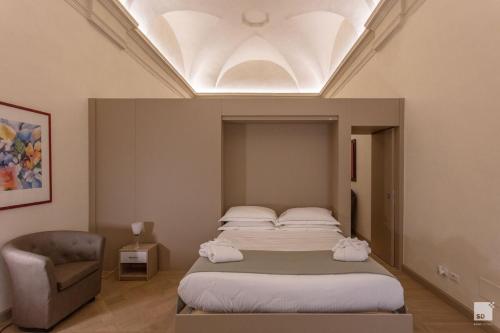 a bedroom with a large bed and a chair at Design Suite in Historical Palace in Bologna