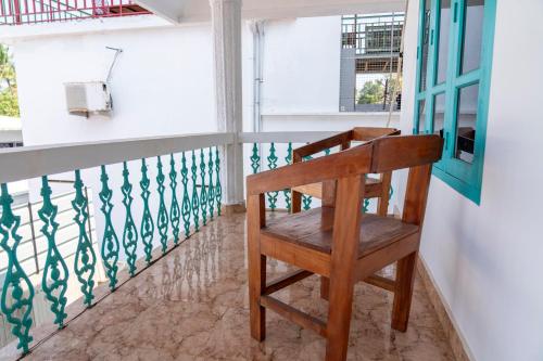 a wooden chair sitting on the balcony of a house at Cliff and Coral Varkala, North Cliff in Varkala