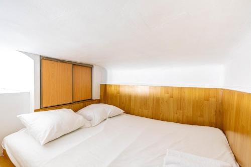 une chambre avec un lit blanc avec une tête de lit en bois dans l'établissement GuestReady - Lovely home near Notre-Dame Cathedral, à Paris