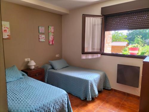 a bedroom with two beds and a window and a tv at La Casina in Celorio