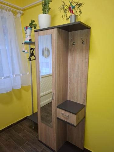 a wooden cabinet in a room with a yellow wall at AMRI Apartman in Balatonföldvár
