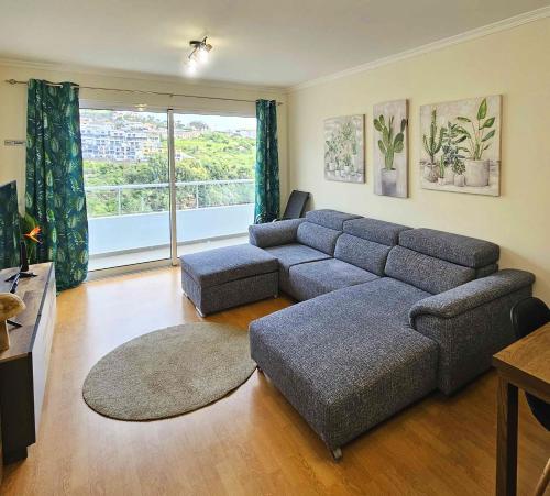 a living room with a couch and a large window at A SELVA T2 in Caniço in Caniço