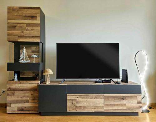 a entertainment center with a television on top of it at A SELVA T2 in Caniço in Caniço
