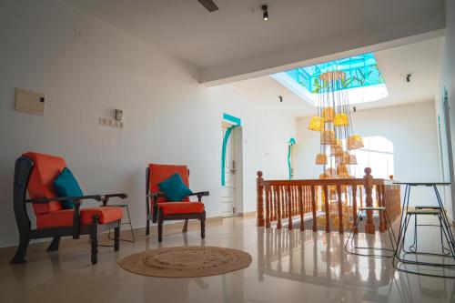 a living room with two chairs and a chandelier at Cliff and Coral Varkala, North Cliff in Varkala