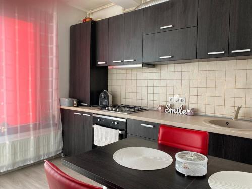a kitchen with a black table and red chairs at Laura Apartament in Târgu-Mureş