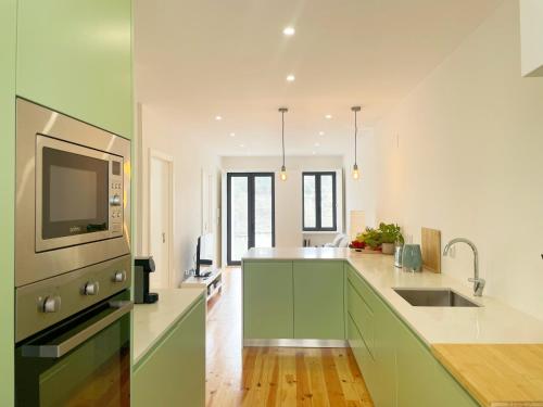 a kitchen with green and white cabinets and a sink at Modern Retreat with Mountain Views in Covilhã