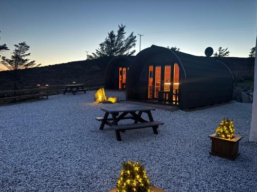 a black tent with a picnic table and christmas trees at Stoer Pods - Suilven Pod in Lochinver