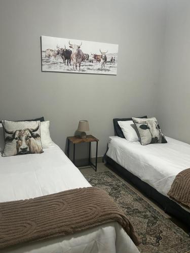 a bedroom with two beds and a picture of deer at Kufihliwe Lodge in Ingogo