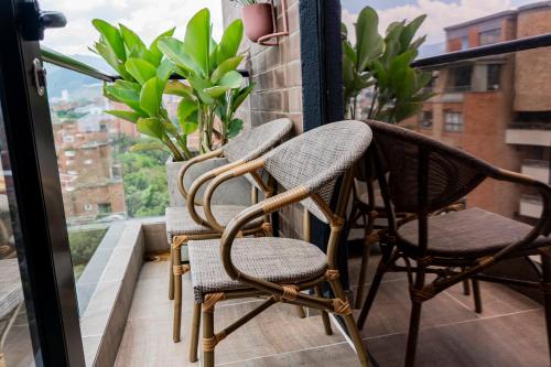 two chairs sitting on a balcony looking out a window at Luxury Apartments Prana By Cadissa in Medellín
