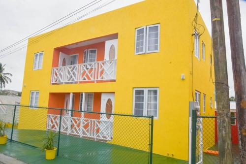 a yellow house with a fence in front of it at ZenBreak Grateful no2 1bd B in Bridgetown