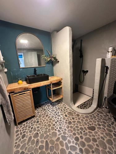 ein Badezimmer mit Waschbecken und Spiegel in der Unterkunft Casa de basalto in Caniço