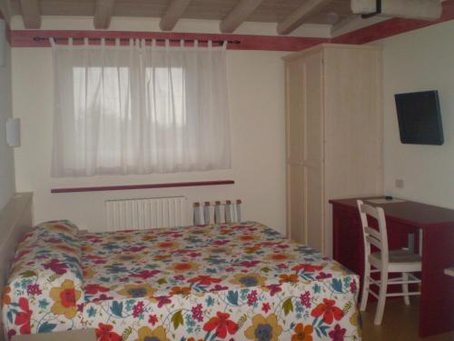 a bedroom with a bed and a desk and a window at Osteria delle 3V in Gignese