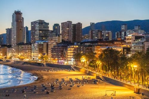 a view of a beach with a city at night at Apartamentos Brisas del Poniente in Benidorm