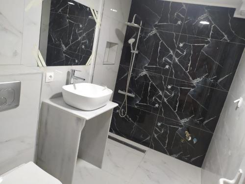a bathroom with a sink and a black marble wall at Bakery apartments in Perea
