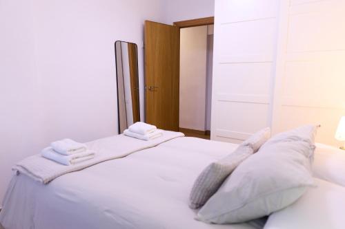 un letto bianco con cuscini e asciugamani bianchi di Apartamento pobla farnals playa precioso a Las Canteras