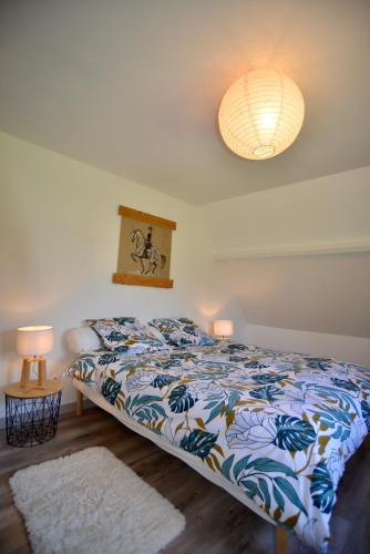 - une chambre avec un lit avec une couette colorée et 2 lampes dans l'établissement Gîte de la ferme Cour Lecoq, à Pierrefitte-en-Auge