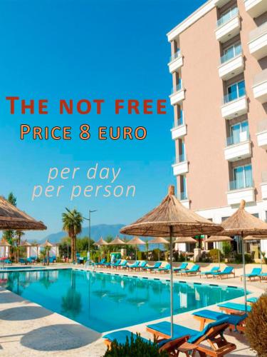 a swimming pool with chairs and umbrellas in front of a building at Old Beach Apartments in Vlorë