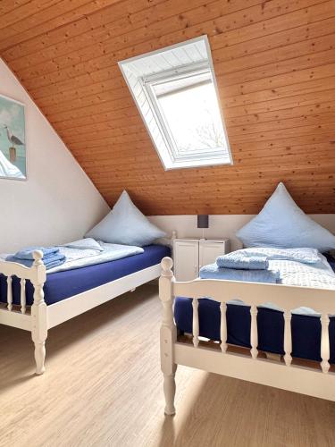 two beds in a attic bedroom with a skylight at Bensersiel Ferienwohnung Matrose mit Balkon und Garten in Bensersiel