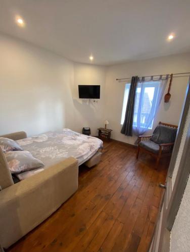 una camera da letto con un letto, un divano e una televisione di Maison à la campagne Grande cuisine tous équipés, grand salon , 3 chambres avec lits doubles, salle de bain et toilettes a Fournols