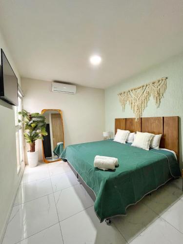 a bedroom with a bed with a green comforter at Departamento planta baja con alberca a 5 min de playa! in Manzanillo