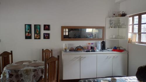 a kitchen with white cabinets and a table and a table and a window at Espaço familiar em Cananeia SP in Cananéia