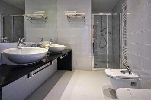 a white bathroom with two sinks and a shower at Hotel Bażantowo Sport in Katowice