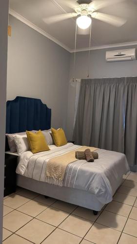 a bedroom with a bed with yellow pillows and a ceiling at Emoyeni Malelane Lodge in Malelane