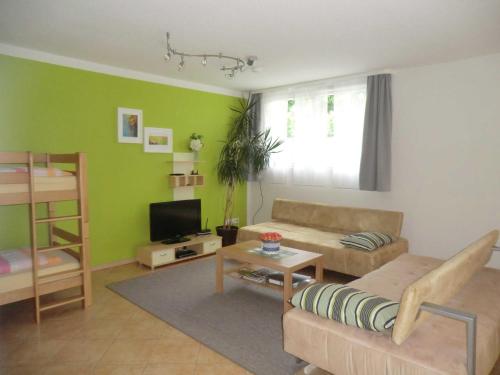a living room with green walls and a couch and a table at Ferienwohnung Koch in Rust