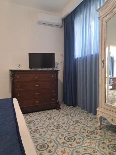a bedroom with a dresser with a tv and a mirror at Paomà Sorrento in Agropoli