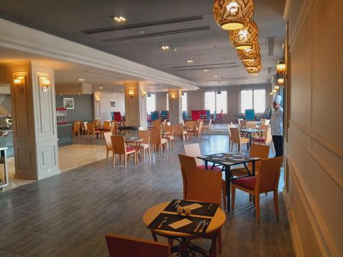 a dining room with tables and chairs in a restaurant at Oriental grand Plaza in Madinat Al Ashir min Ramadan