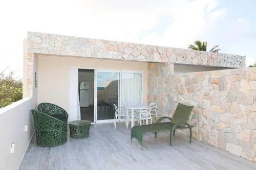 a patio with chairs and a table and a stone wall at DUNA HOUSE, apartamento beira mar em ARACAJU in Aracaju