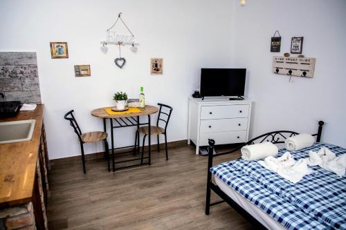 a room with two beds and a table and a television at Privát Szálláshely Dézsafürdővel-Kata Cottage in Szanda