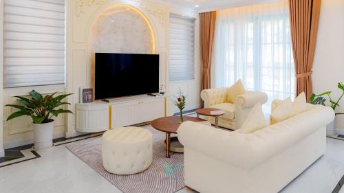 a living room with white furniture and a flat screen tv at DT Retreat - Biệt thự nguyên căn - 3 Phòng ngủ - Novaworld Phan Thiết in Phan Thiet