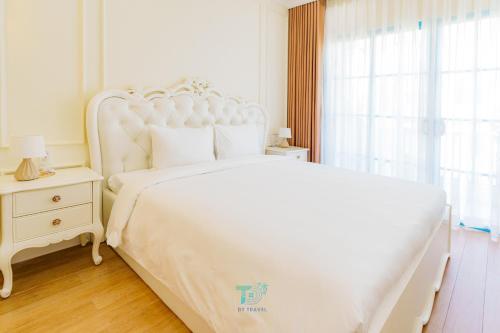 a white bedroom with a white bed and a window at DT Retreat - Biệt thự nguyên căn - 3 Phòng ngủ - Novaworld Phan Thiết in Phan Thiet