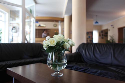 a vase filled with white roses sitting on a table at Hotel Huszcza in Mrągowo