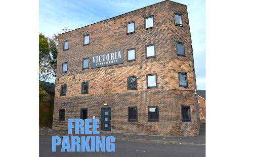 a brick building with a free parking sign on it at OYO Victoria Apartments in Middlesbrough