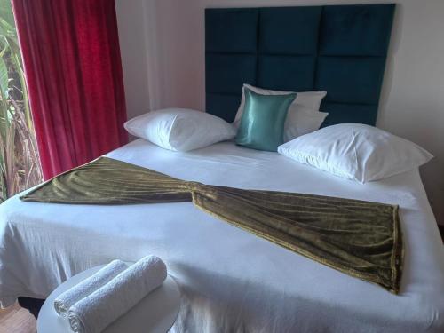 a bed with white sheets and pillows on it at MayBach Hills Palace Guesthouse in Saldanha