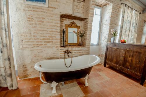a bath tub in a room with a brick wall at La Chambre Bleue in Lauzerte