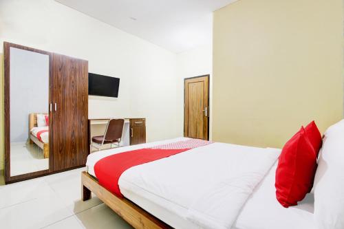 a bedroom with a bed with red pillows and a mirror at Dancenter Pogung Near Near Plaza Ambarrukmo in Kejayan