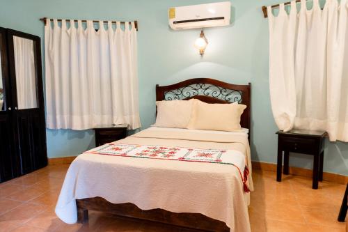 a bedroom with a bed and two tables and curtains at Hotel Paraíso Encantado in Xilitla