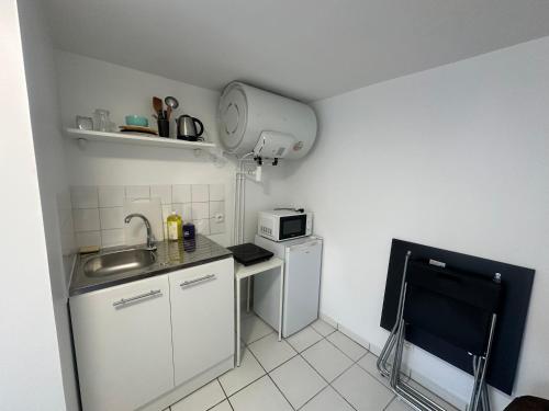 une petite cuisine avec un évier et un micro-ondes dans l'établissement STUDIO PARIS 2e ARRONDISSEMENT, à Paris